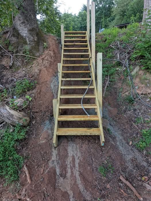 Long wooden staircase being built up a steep wooded bank